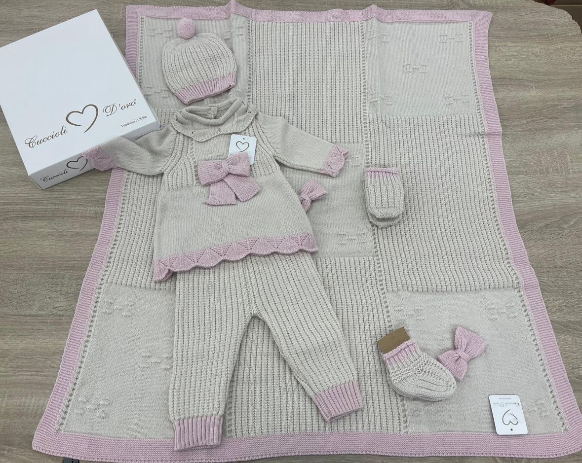 Un vestito lavorato a maglia per neonati è appoggiato su un tavolo di legno accanto a una scatola.