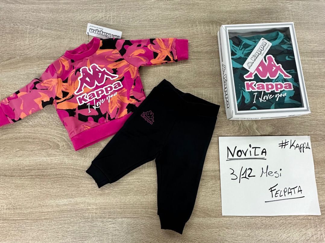 Una felpa rosa della Kappa e dei pantaloni neri sono su un tavolo di legno.