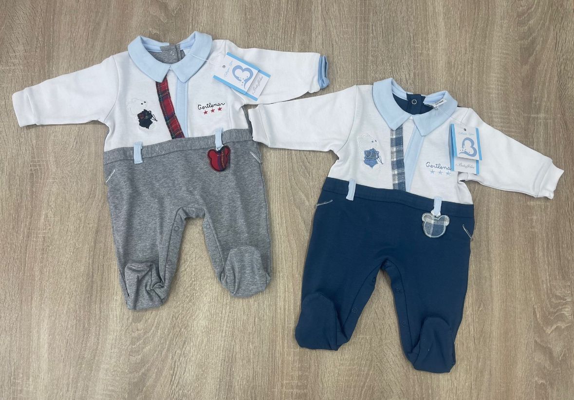 Due vestitini per neonati sono appoggiati su un tavolo di legno.