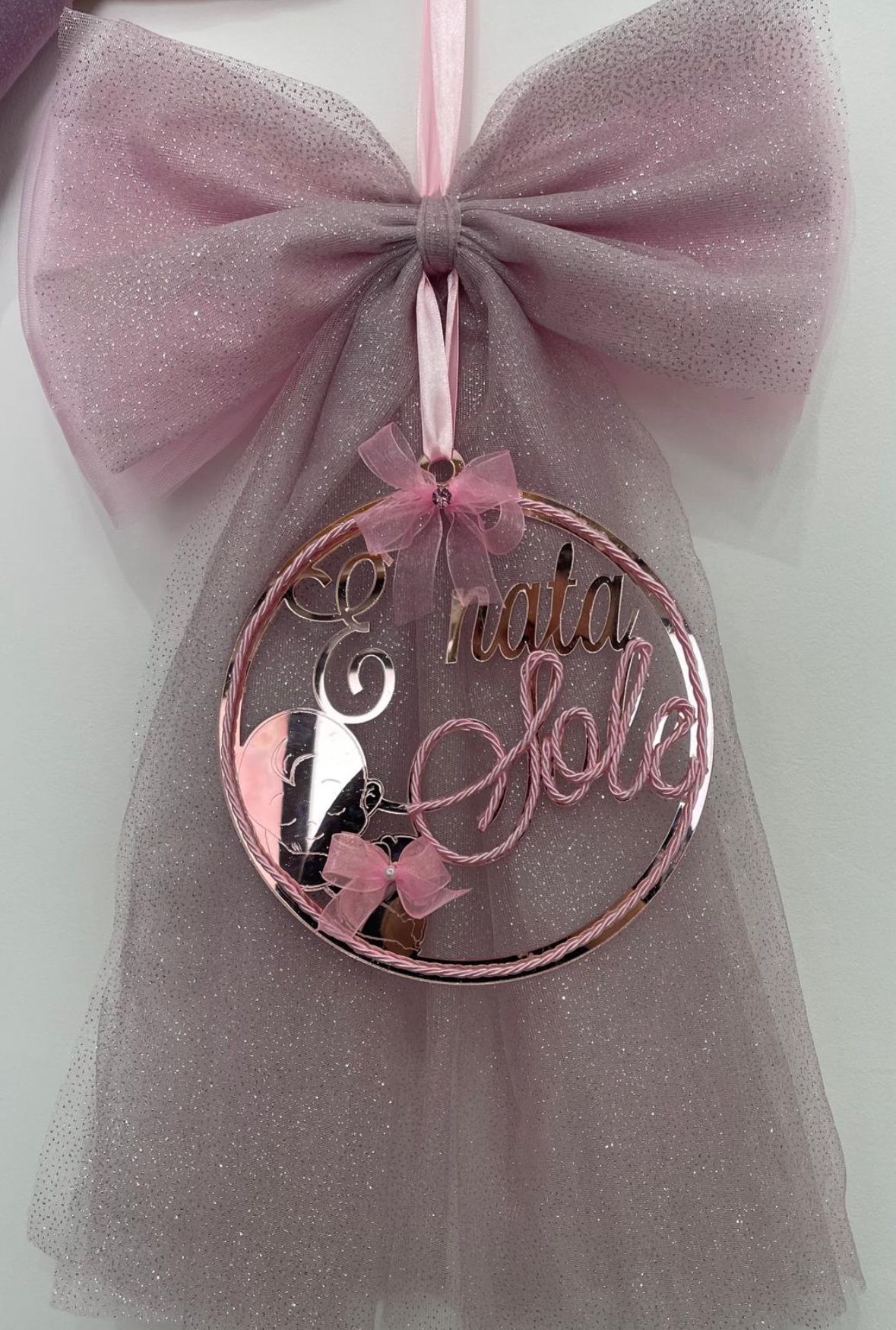 Un addobbo natalizio con un fiocco rosa è appeso al muro.