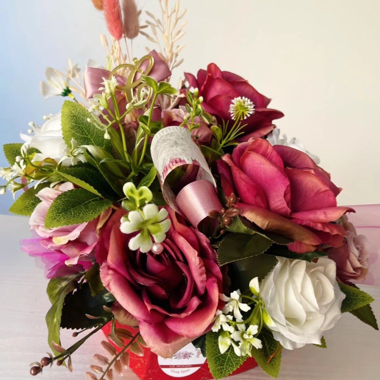 Un mazzo di rose rosa e fiori bianchi in una scatola rossa