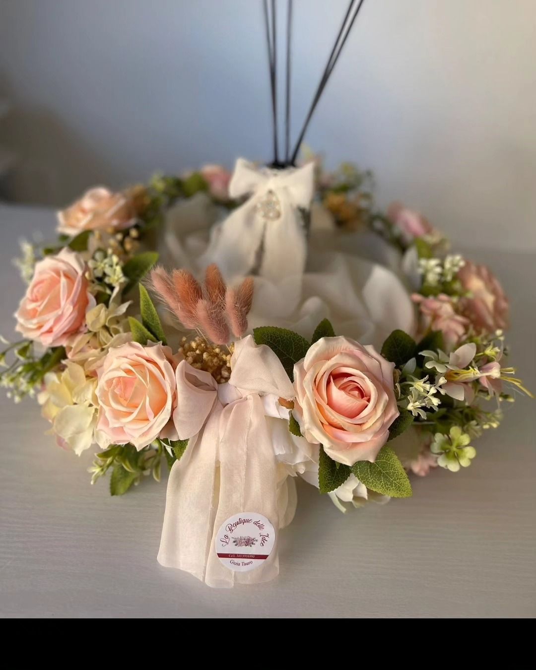 Una corona di rose rosa e verde è appoggiata su un tavolo.