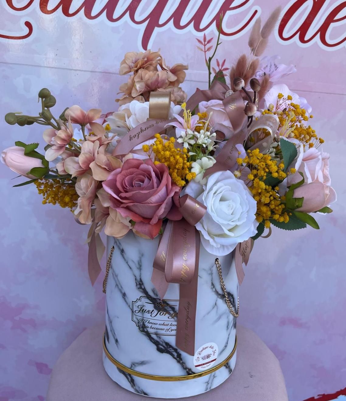 Una scatola di marmo bianco piena di fiori rosa e gialli