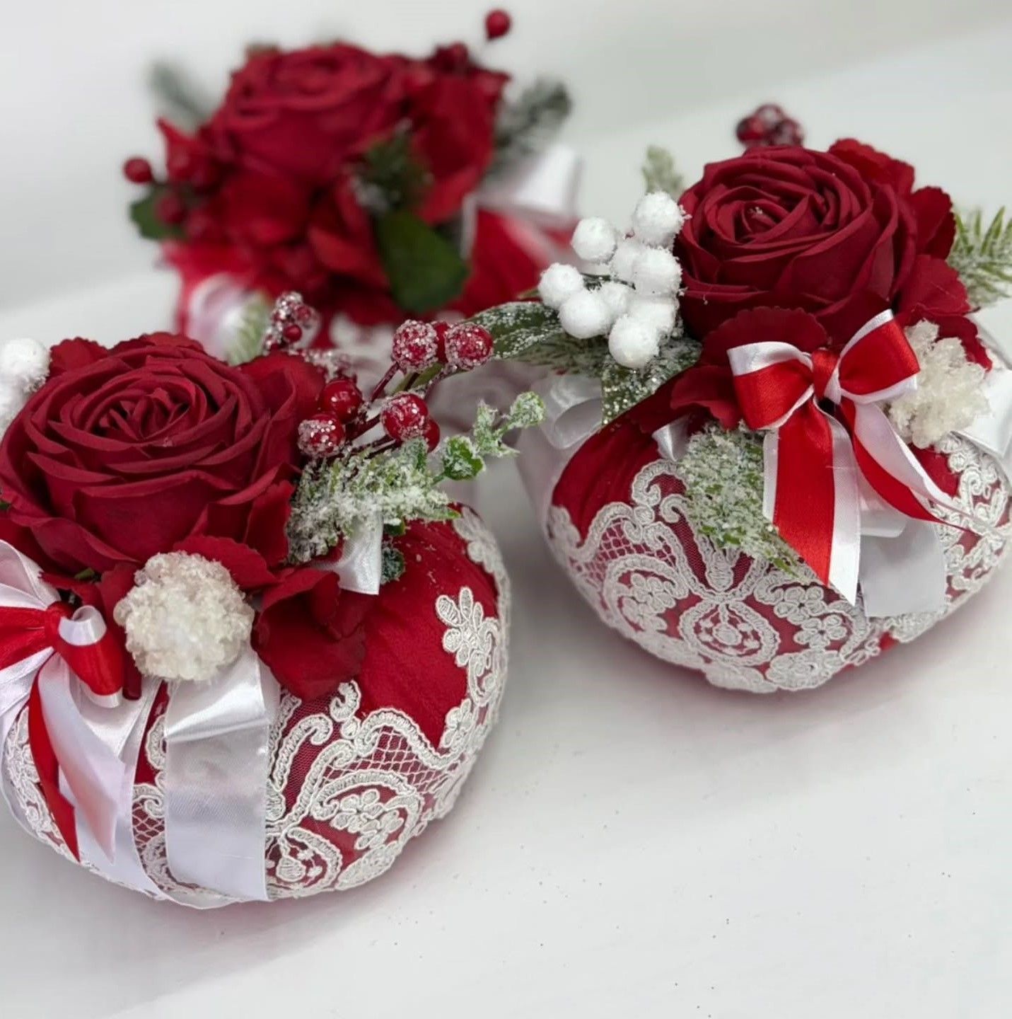 Due ornamenti rossi e bianchi con rose rosse e bacche bianche