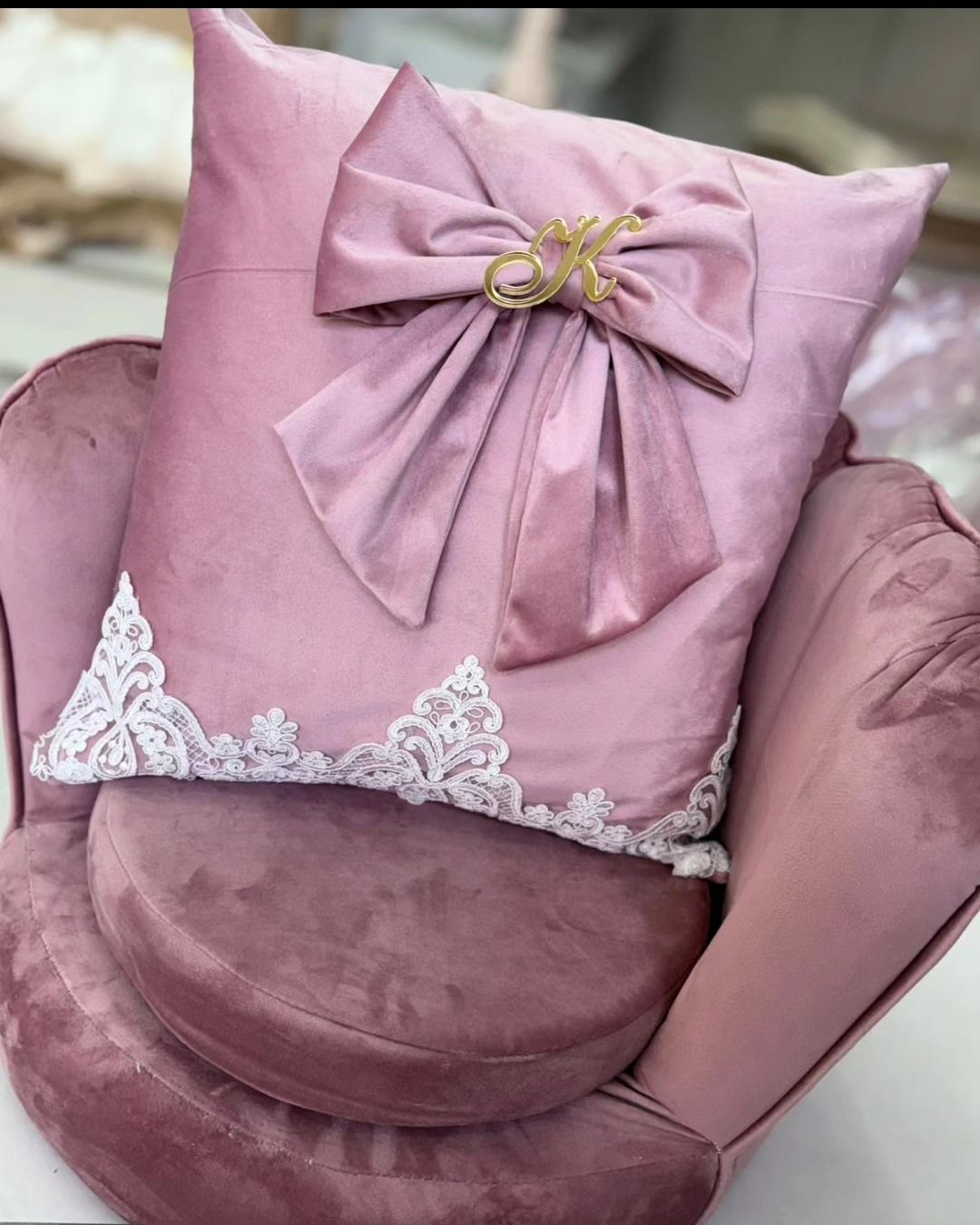 Un cuscino rosa con un fiocco è appoggiato su una sedia rosa.