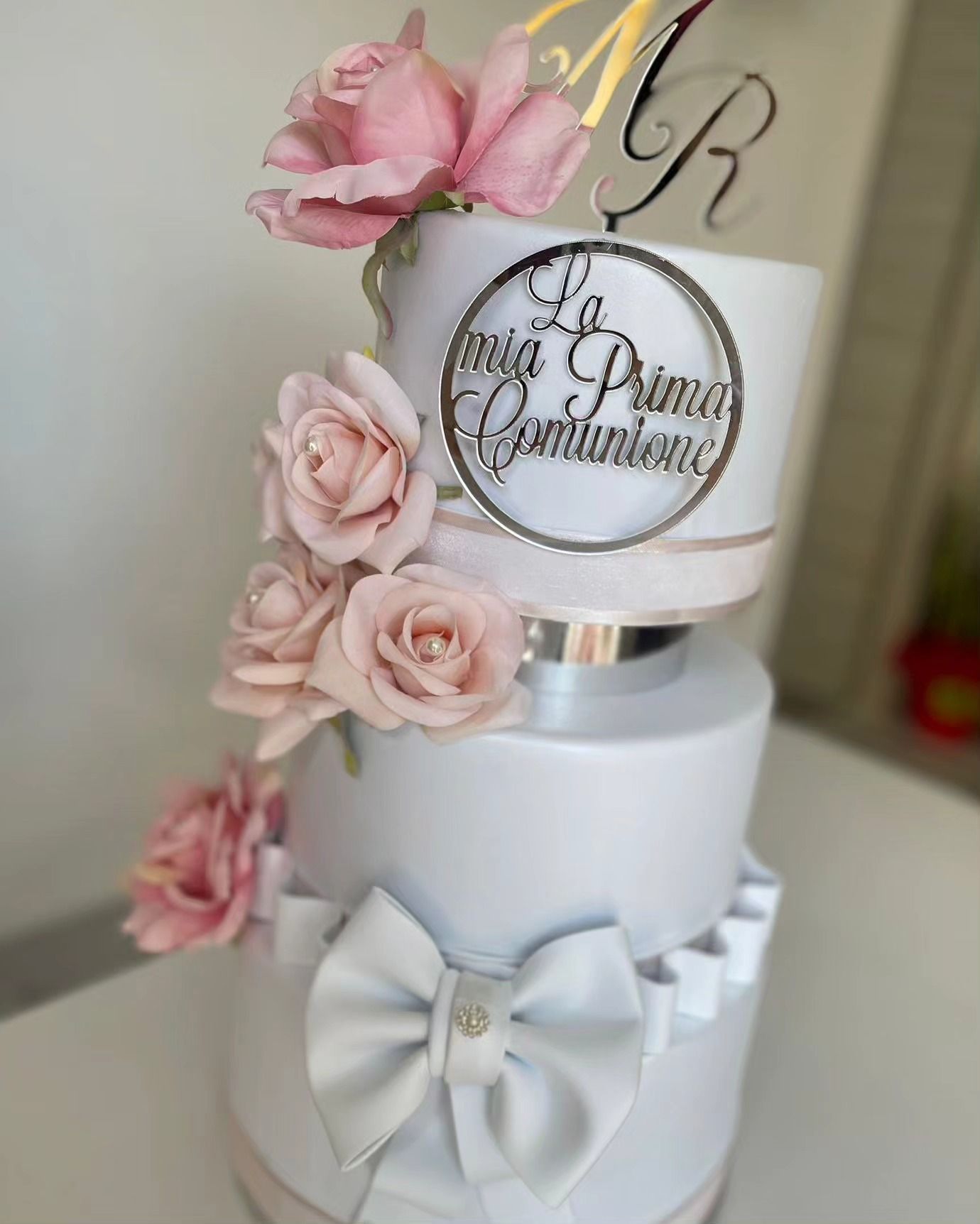 Una torta bianca con rose rosa e un fiocco sopra