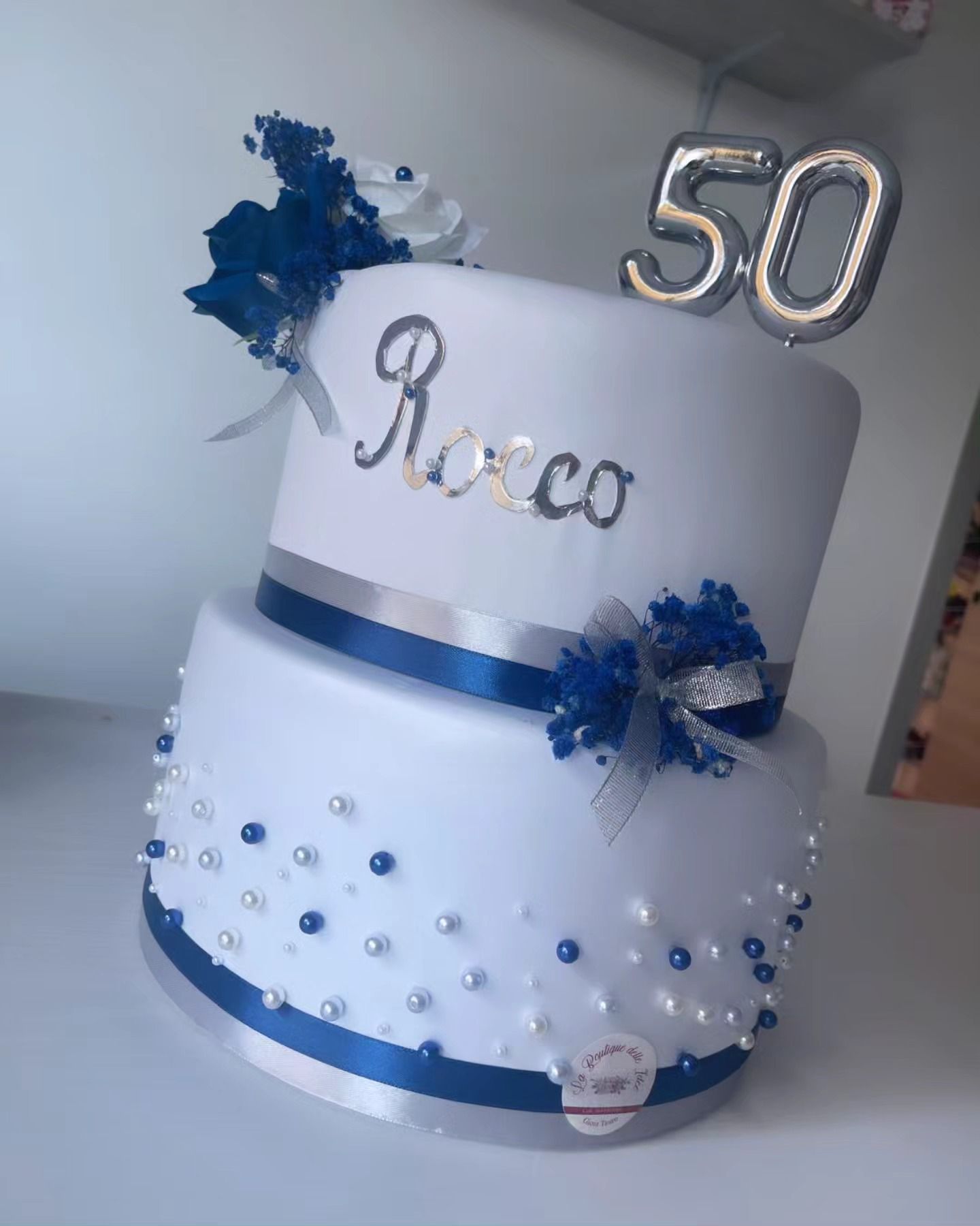 Una torta bianca e blu con il numero 50 in cima