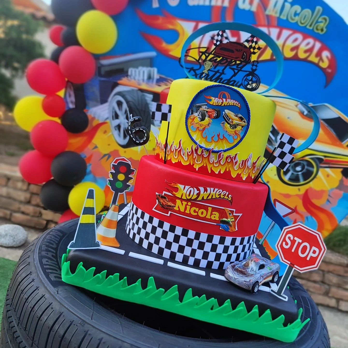 Una torta di compleanno hot wheels è appoggiata su uno pneumatico