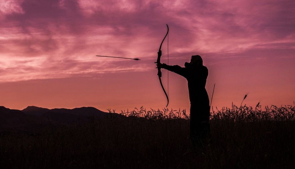Man shooting an arrow at sunset