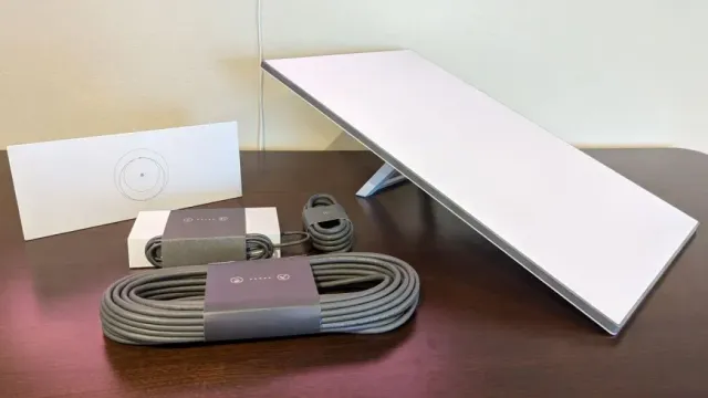 A table with a laptop , cables , and a charger on it.