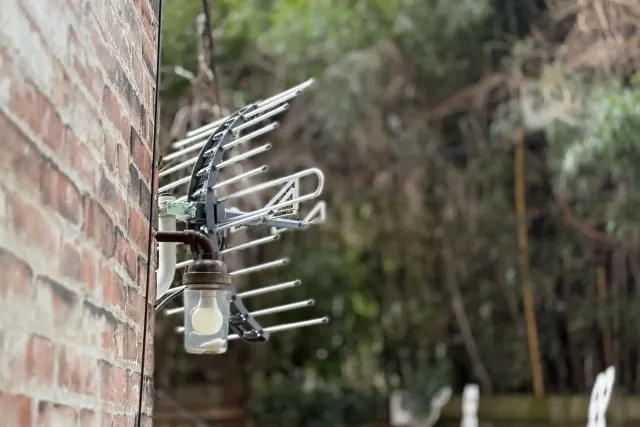 A brick wall with an antenna and a light attached to it.