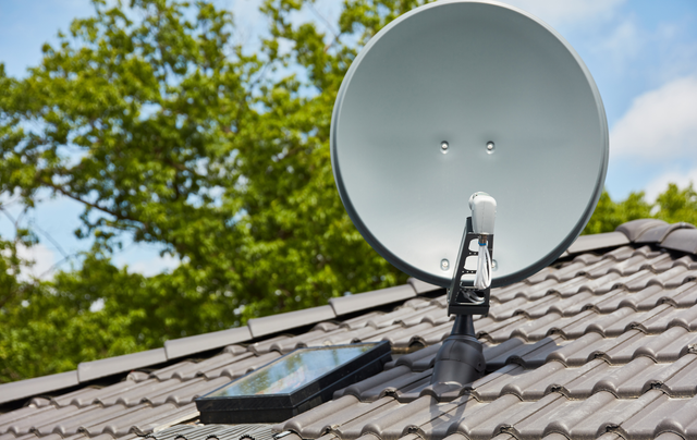 A satellite dish is sitting on top of a tiled roof.