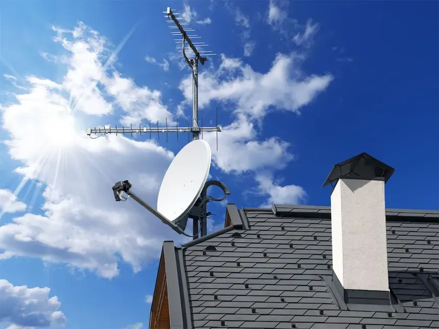 A satellite dish is sitting on top of a roof.