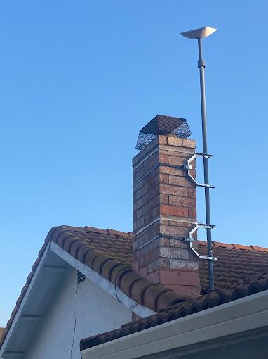 A chimney on the roof of a house with a blue sky in the background.