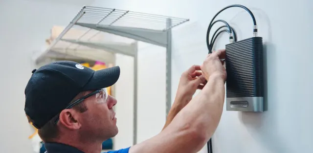 A man is installing a router on a wall.