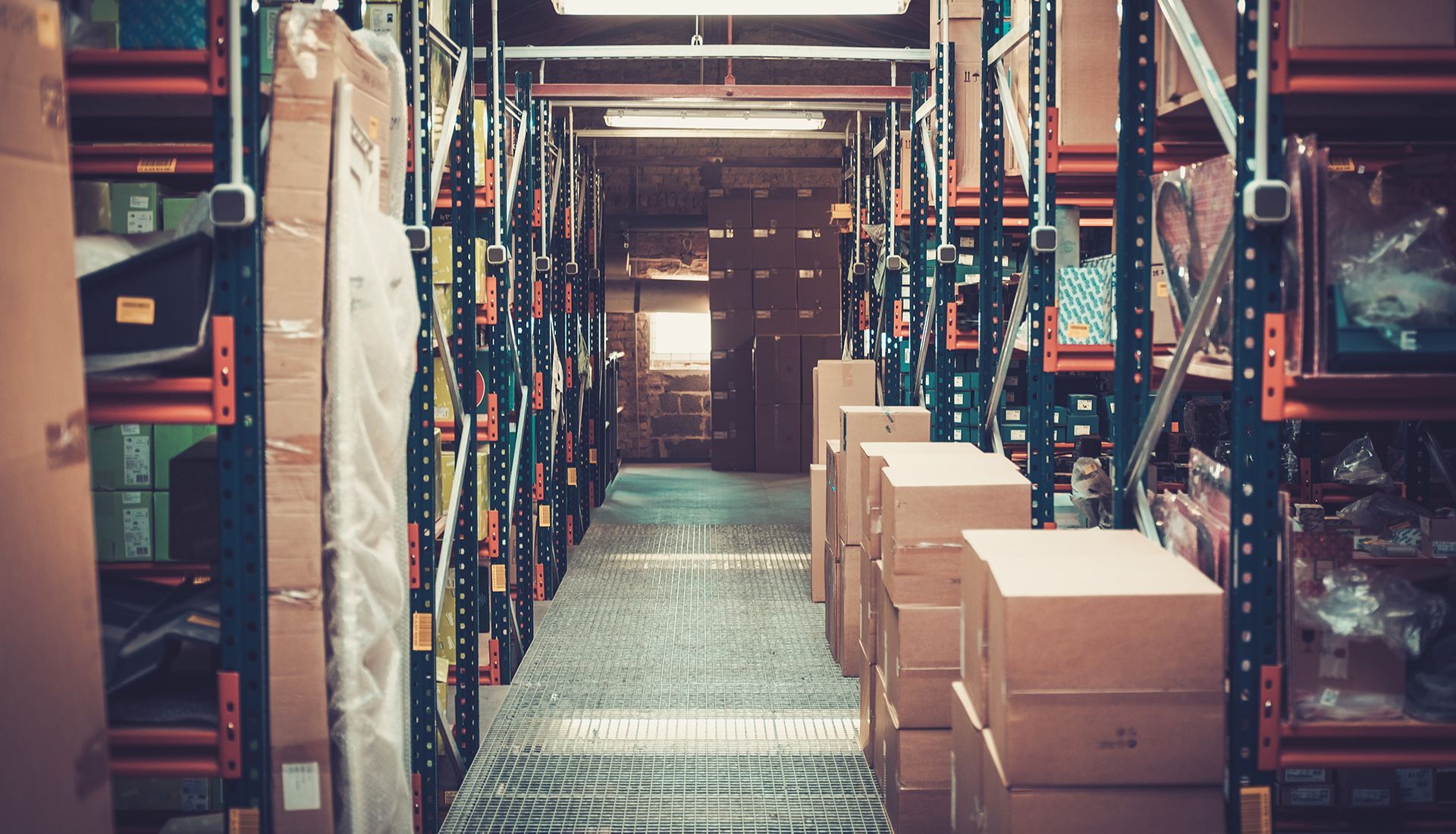 Warehouse aisle lined with shelves and cardboard boxes.