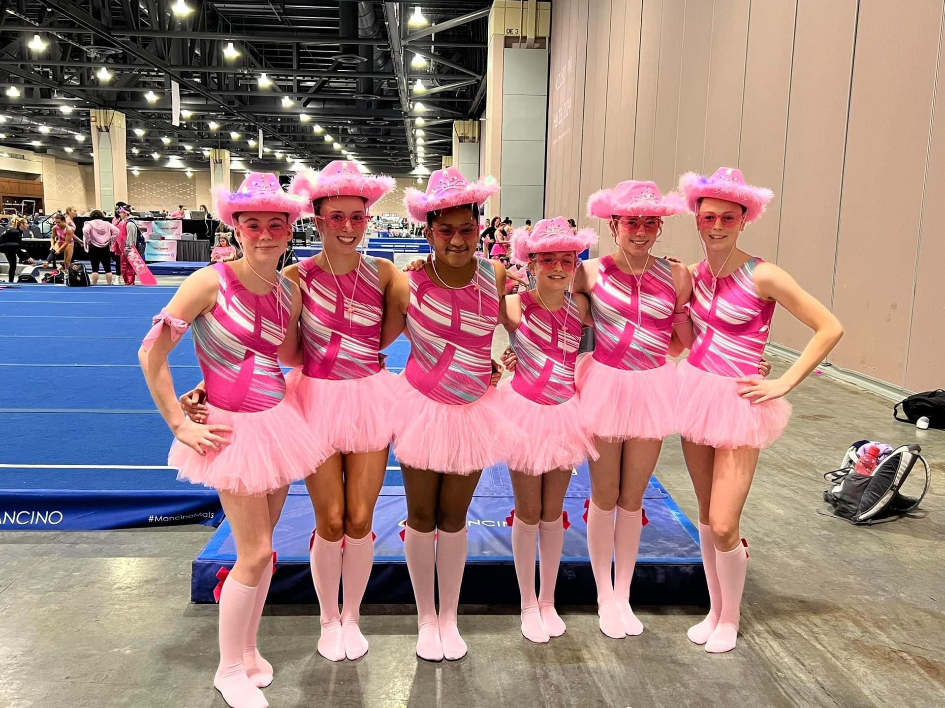 A group of women wearing pink tutus and cowboy hats are posing for a picture.