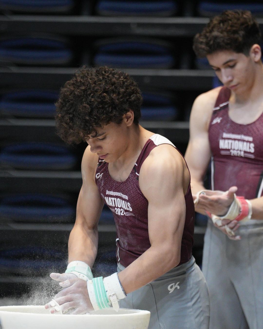 Two young men are practicing gymnastics in a gym.