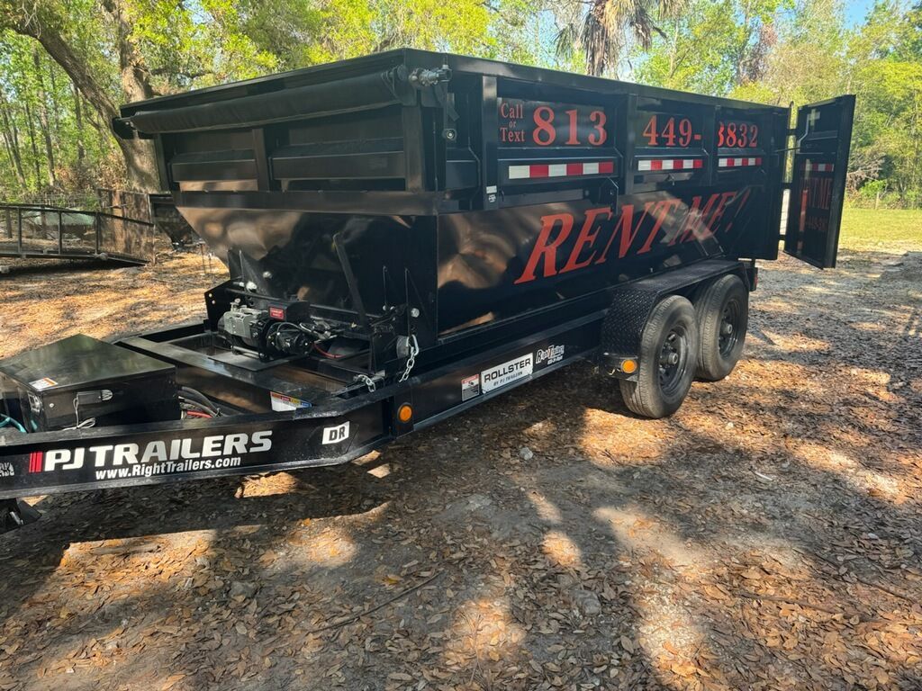 Black dump trailer with open tailgate, parked outdoors.
