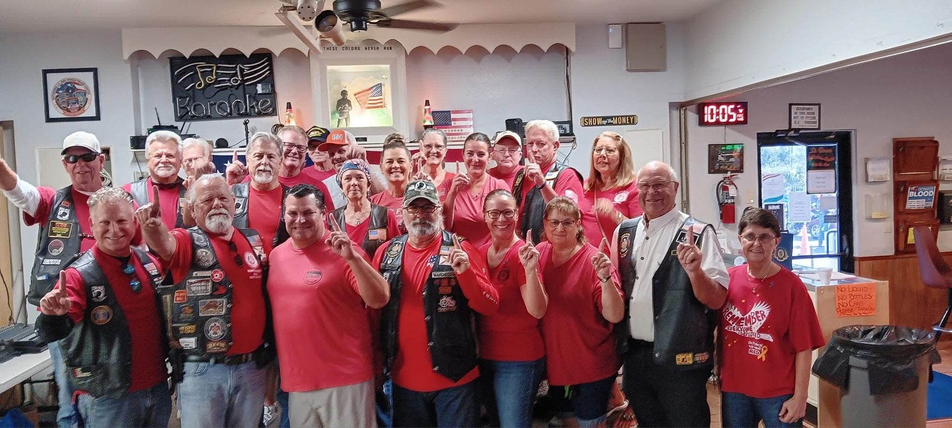 Group of people in red shirts, indoors, posing and making peace signs.