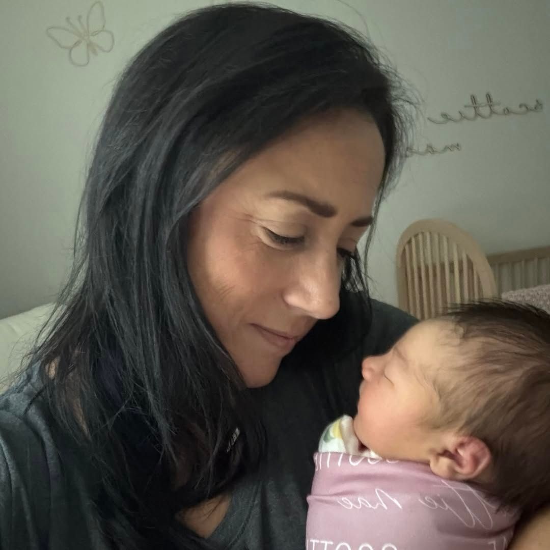 Woman cradling a newborn, both looking at each other lovingly. Inside, light setting.