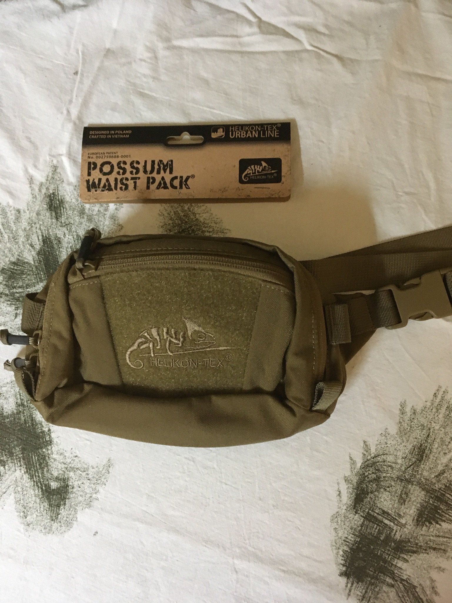 Hellbraune Hüfttasche neben einem Karton mit der Aufschrift „POSSUM-HÜFTTASCHE“.