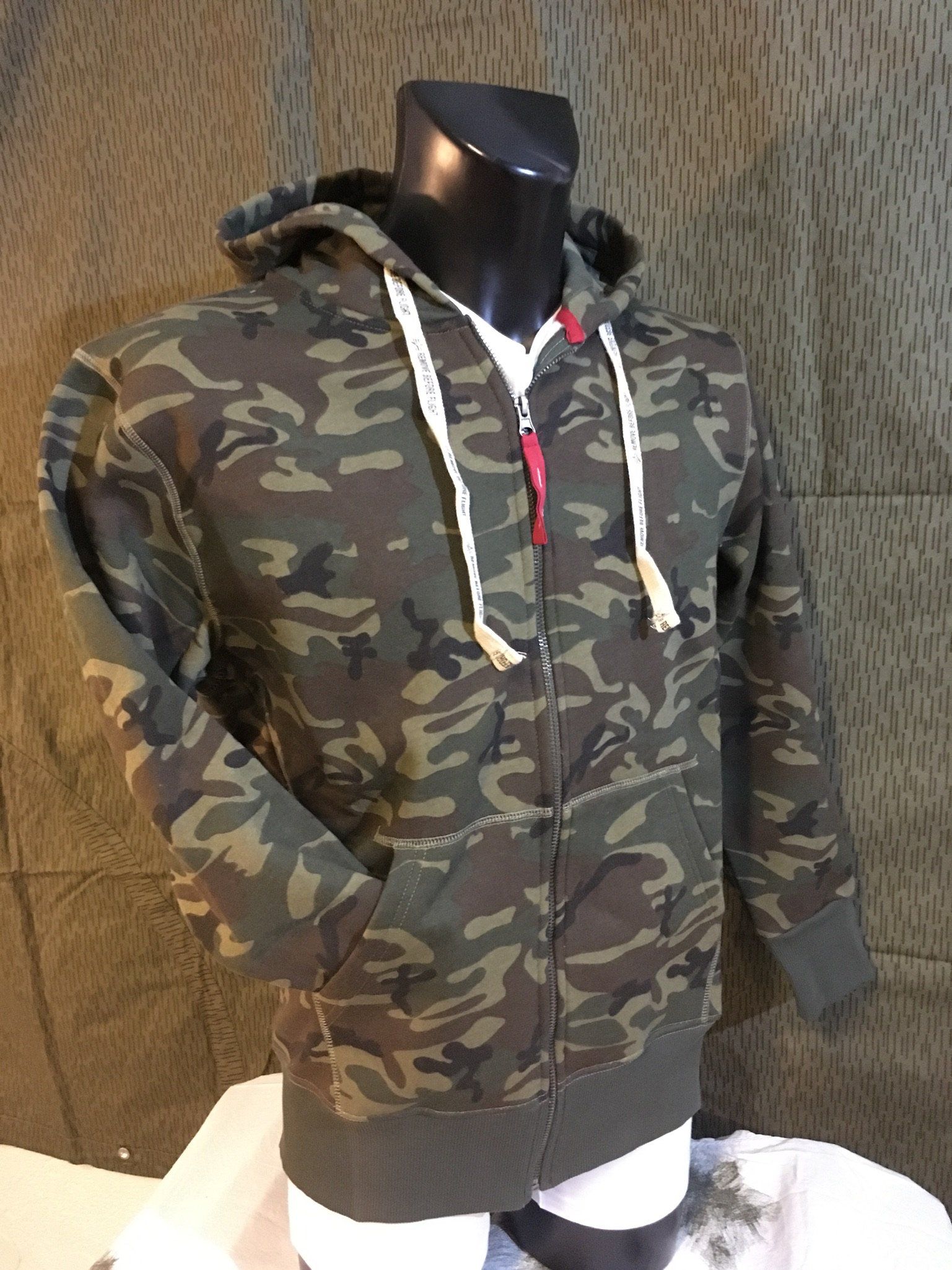 Camouflage-Kapuzenpullover mit Reißverschluss an einer Schaufensterpuppe, in den Farben Braun, Grün und Hellbraun.