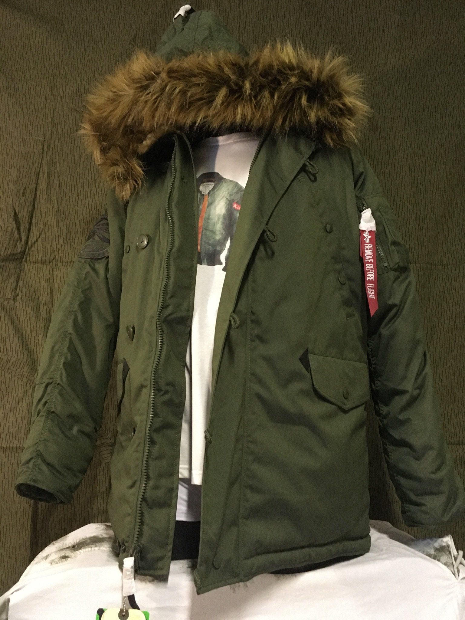 Grüne Parkajacke mit Kunstpelzkapuze über einem weißen T-Shirt.