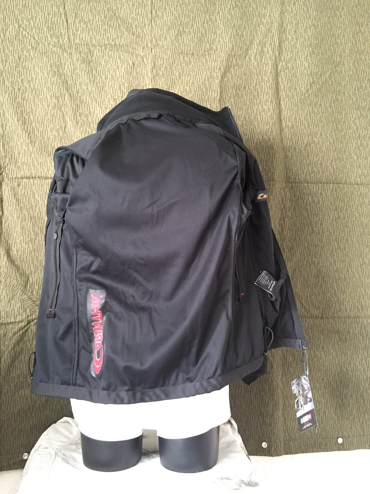 Schwarze Jacke an einer Schaufensterpuppe, mit einem Etikett. Camouflage-Hintergrund.