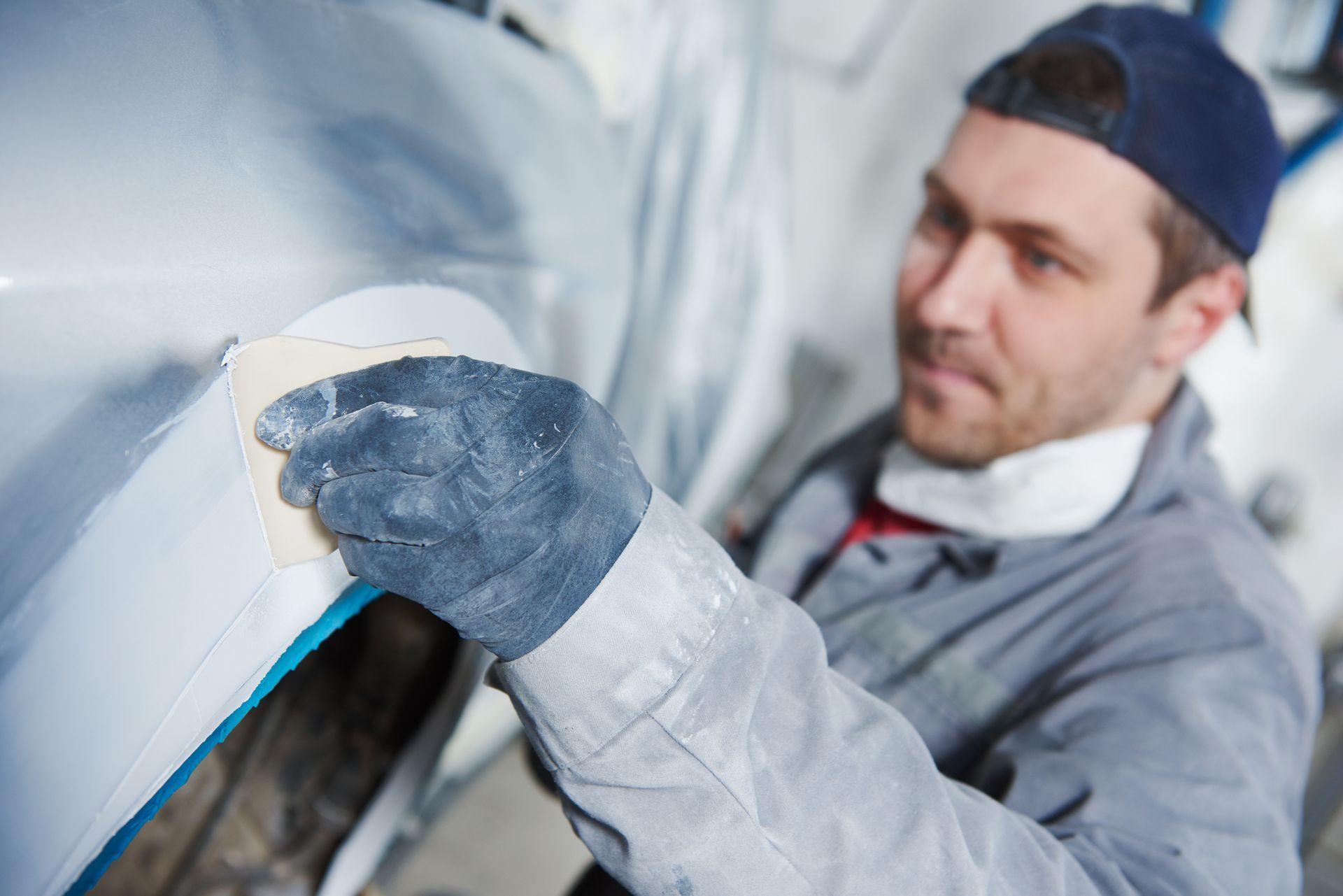 Man from Lindsay’s Auto Body & Paint working on a collision repair by plastering the automobile in R