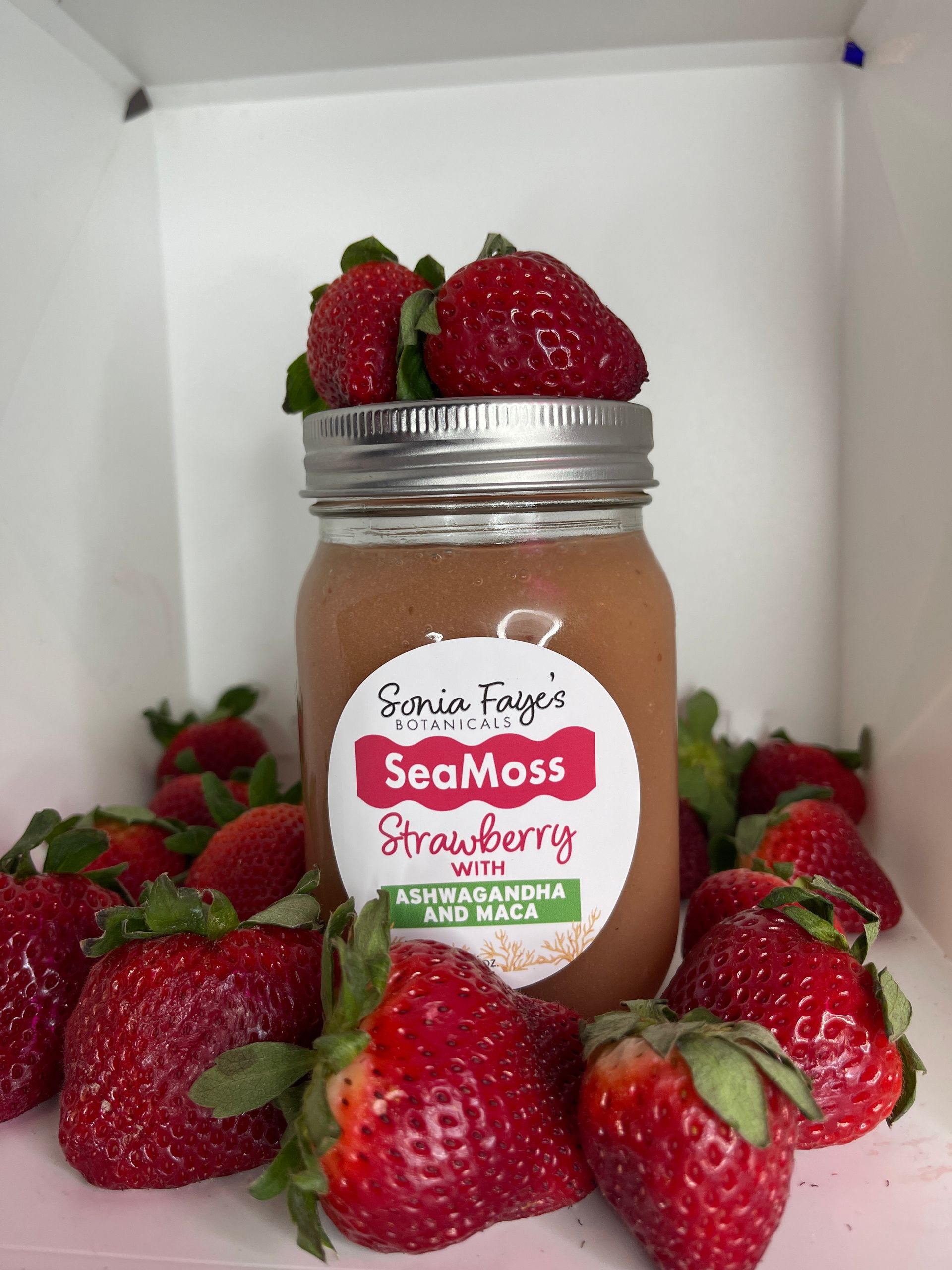 A jar of strawberry sea moss is surrounded by strawberries