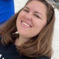A woman is smiling for the camera while wearing sunglasses and a black shirt.