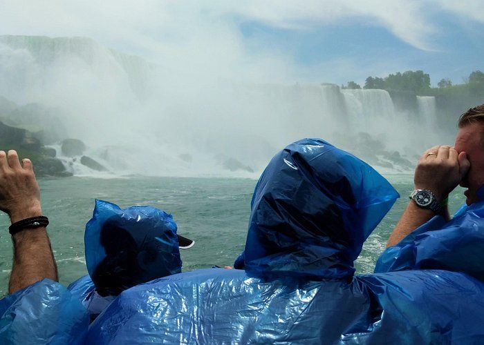 People in blue raincoats near Niagara Falls, water cascading.