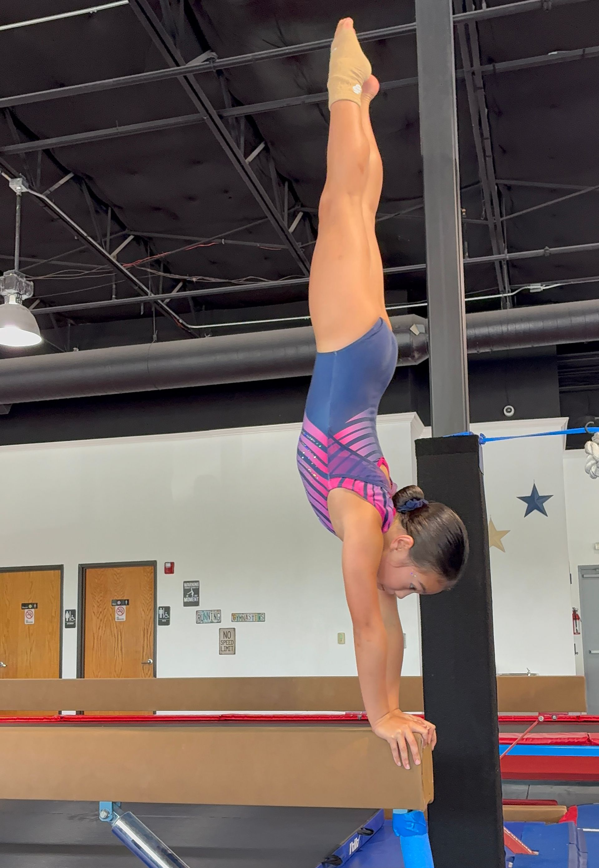 A silhouette of a person doing a handstand on a gray background.