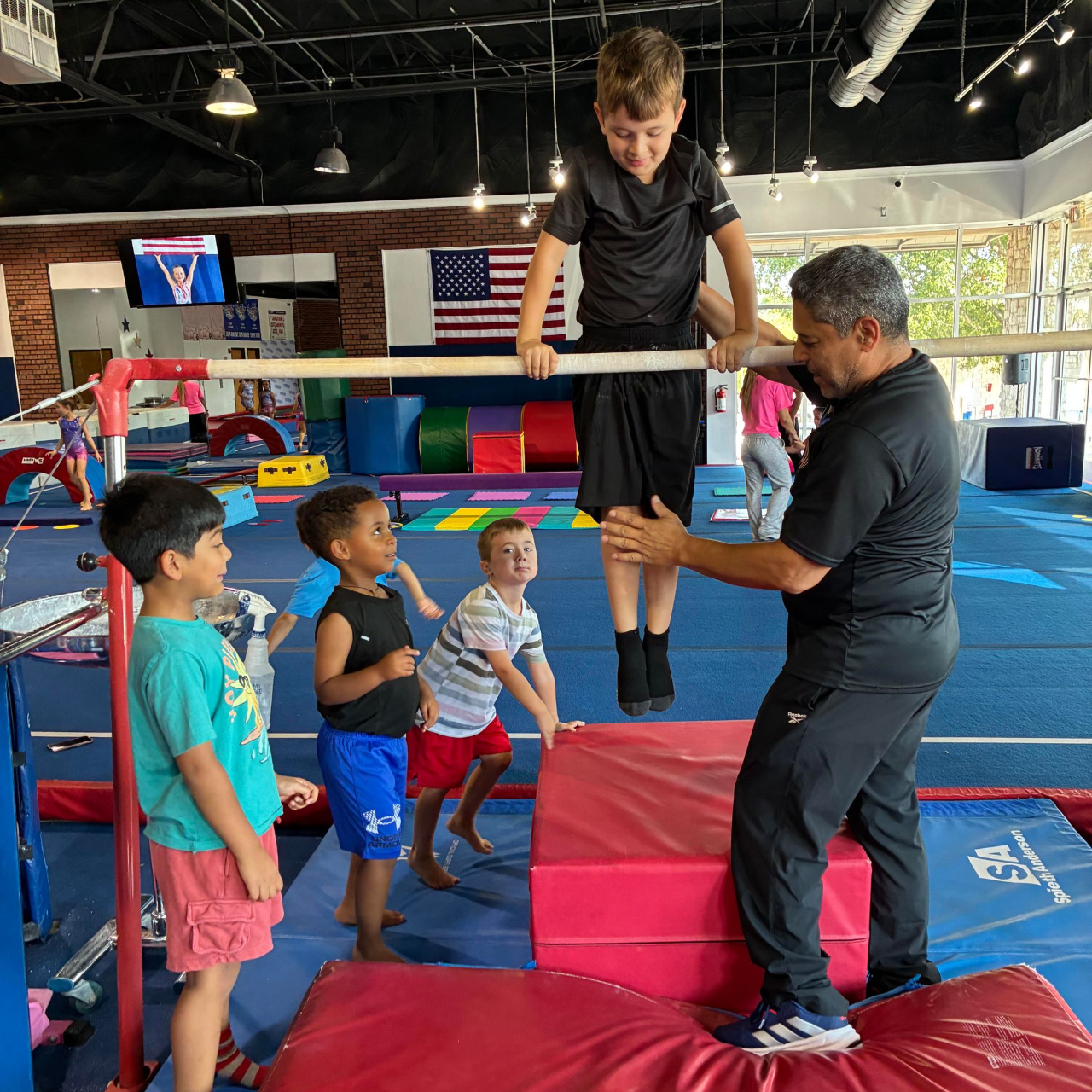 A young boy is doing a handstand on a mat