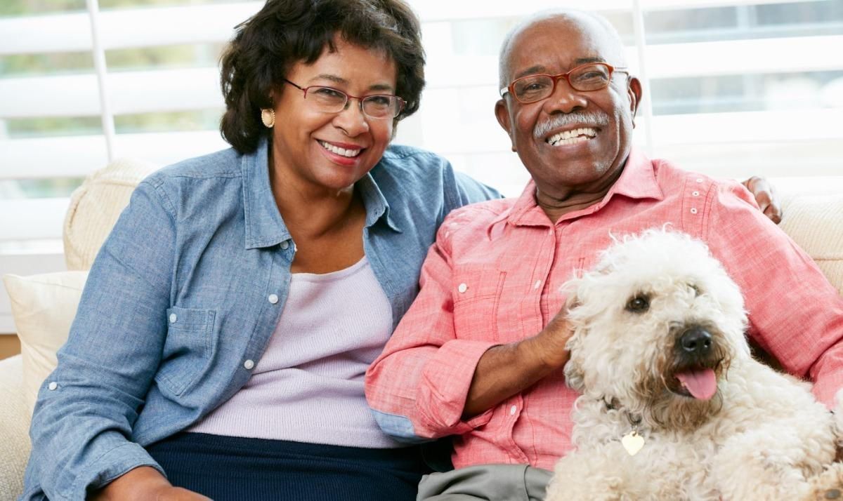 A man and woman are sitting on a couch with a dog.