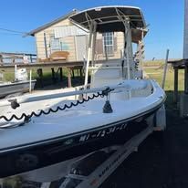 A white boat is parked in front of a house.