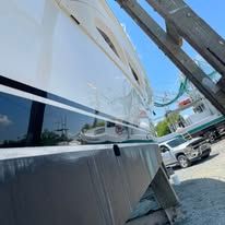 A white boat is parked in a parking lot next to a ladder.
