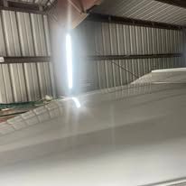A white car is parked in a garage with a light on the roof.