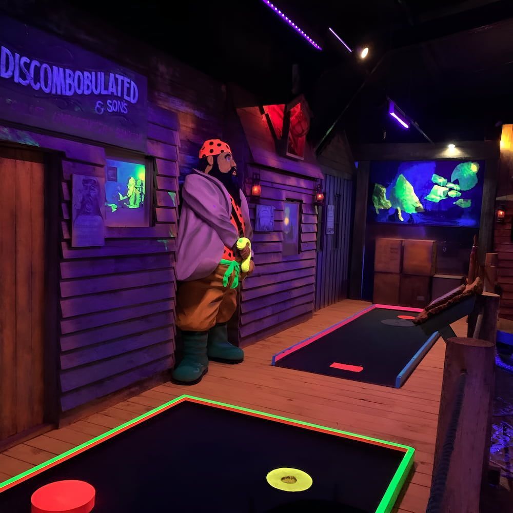 A Man Stands in Front of a Sign That Says Discombobulated — Gold Rush Mini Golf in Warrenheip, VIC