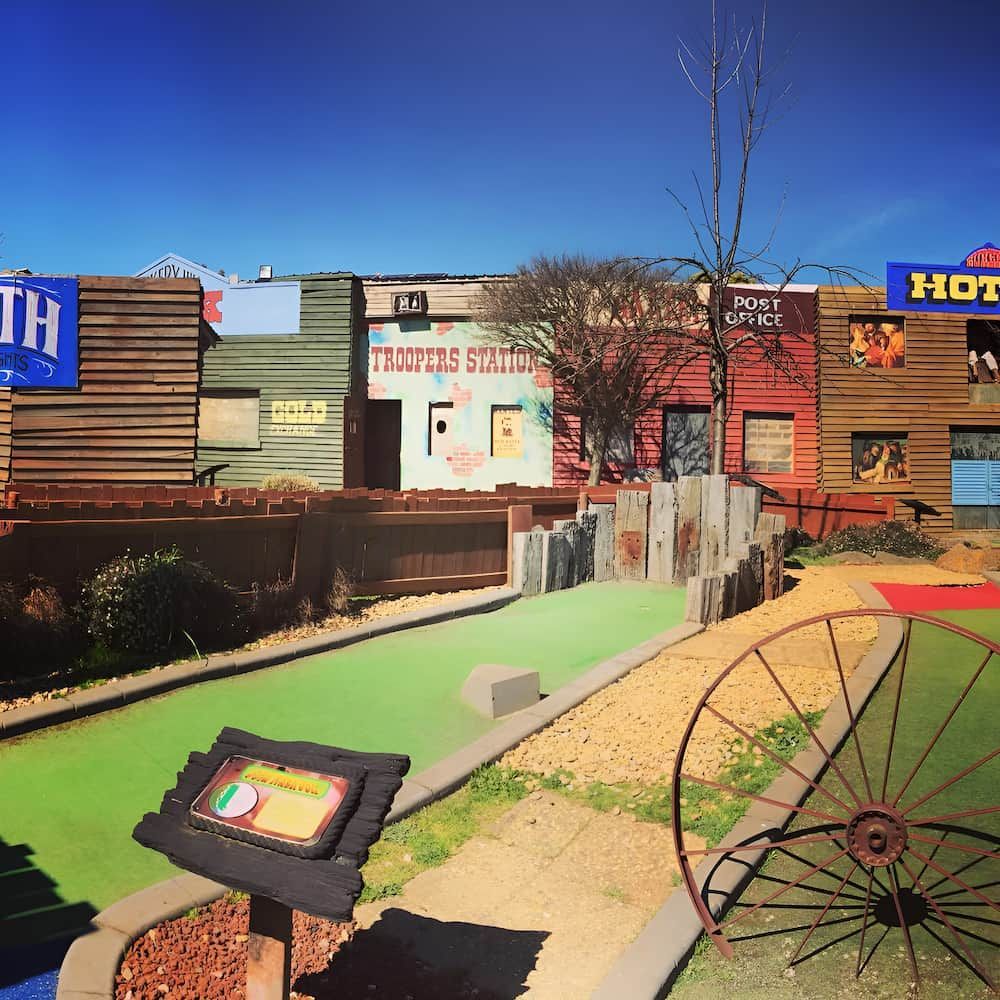 A Row of Buildings With One That Says Hot on It — Gold Rush Mini Golf in Warrenheip, VIC