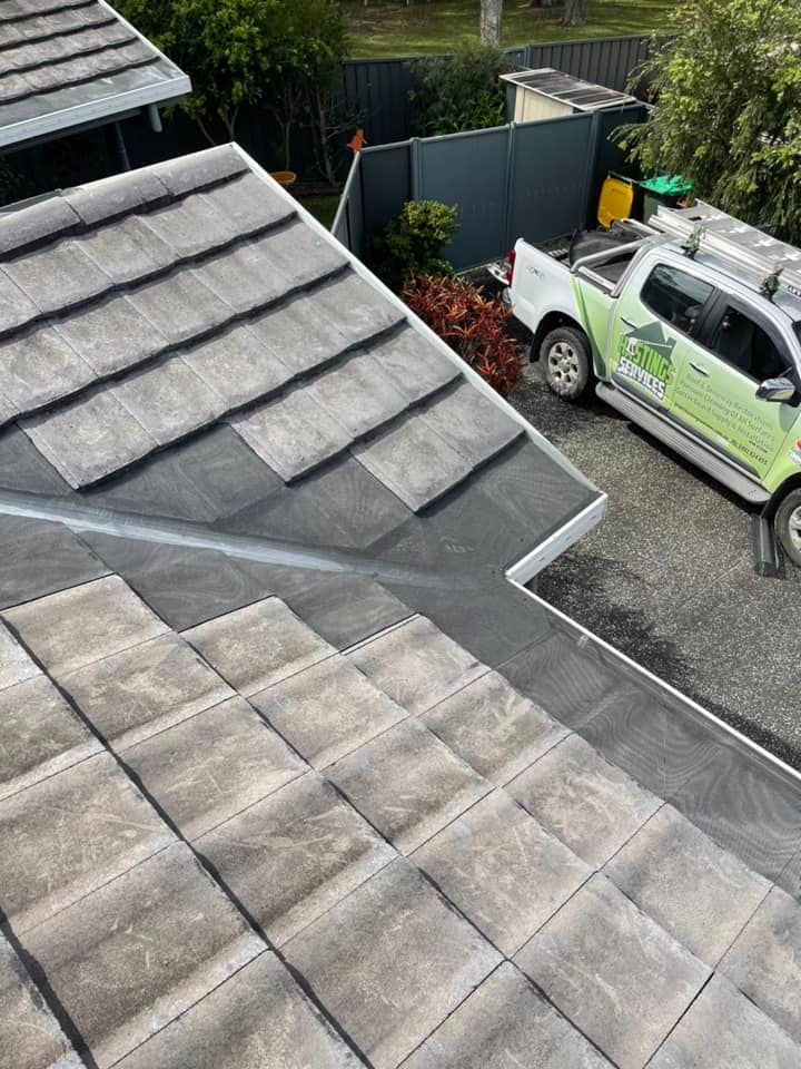 Rooftop with grey tiles and a gutter, a white truck is parked below. — Gutter Guard In Lake Cathie, NSW