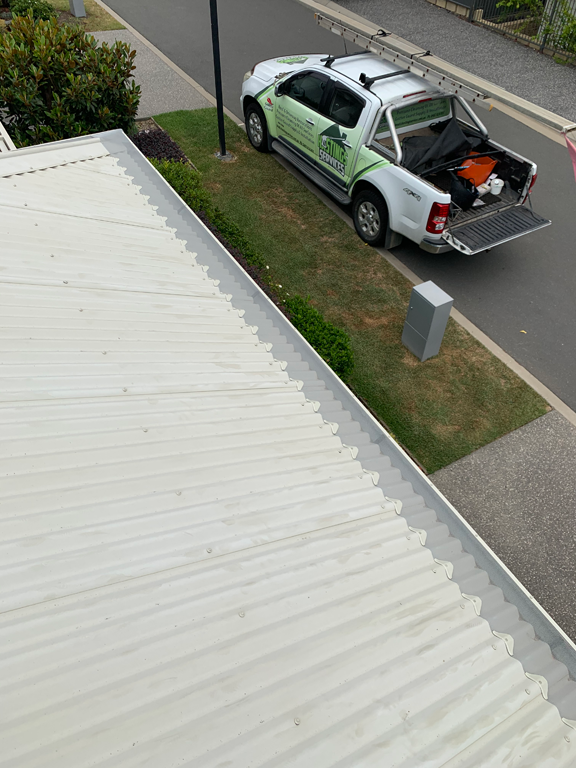 White corrugated roof and silver guttering next to a grassy area with a utility truck. — Gutter Guard In Lake Cathie, NSW