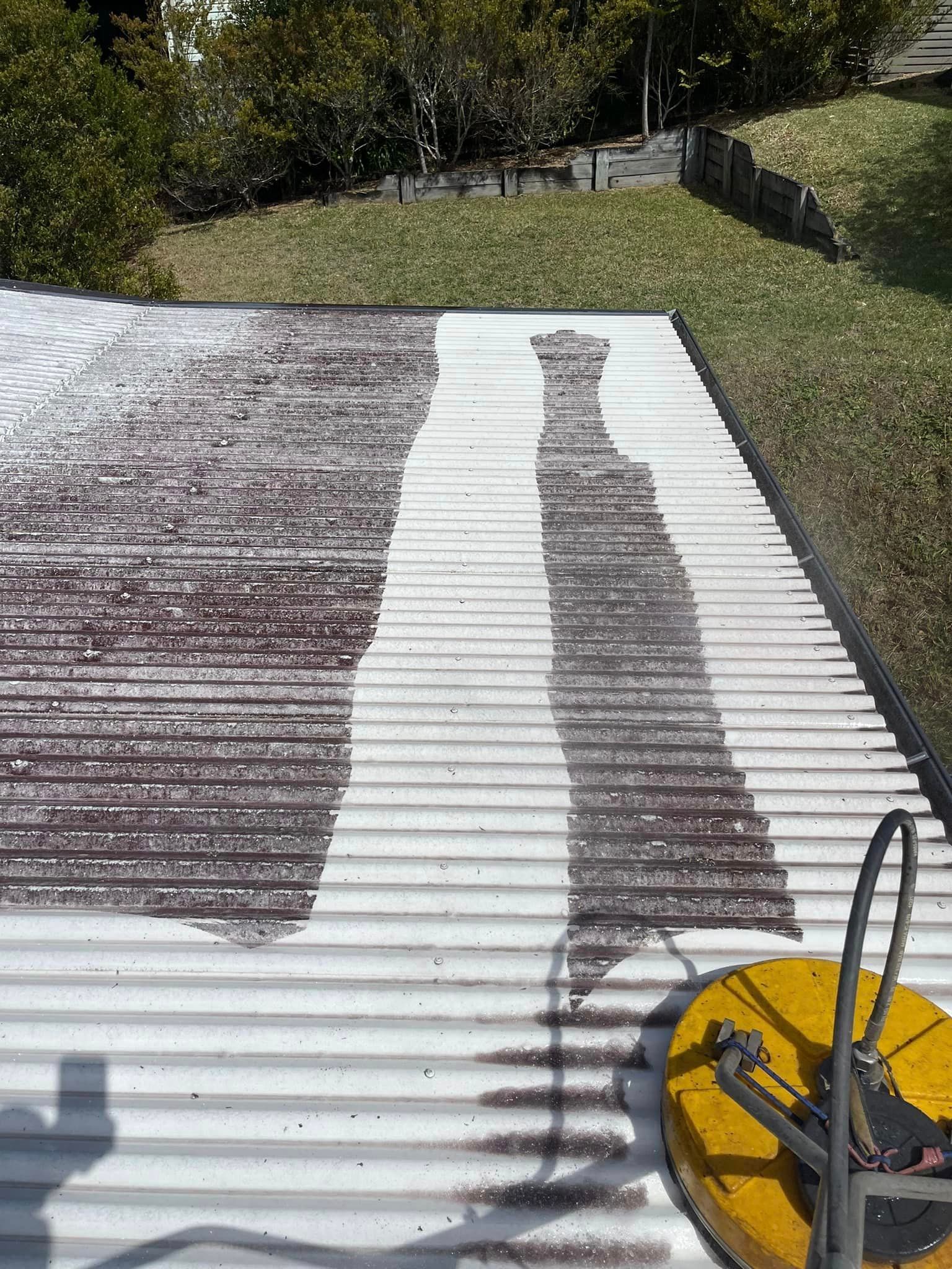 Power washing a rusty corrugated metal roof, showing a clean strip. — Gutter Guard In Lake Cathie, NSW