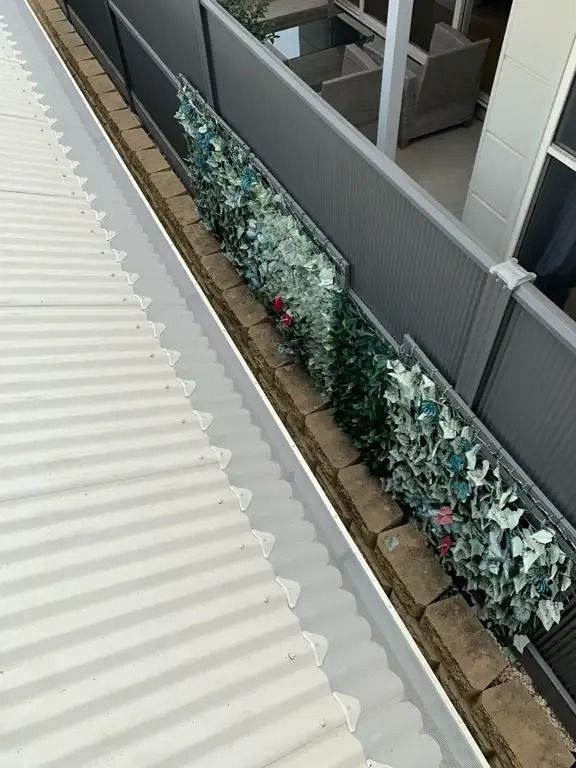 A Gutter With Flowers Growing On It Next To A Fence — Gutter Guard In Lake Cathie, NSW