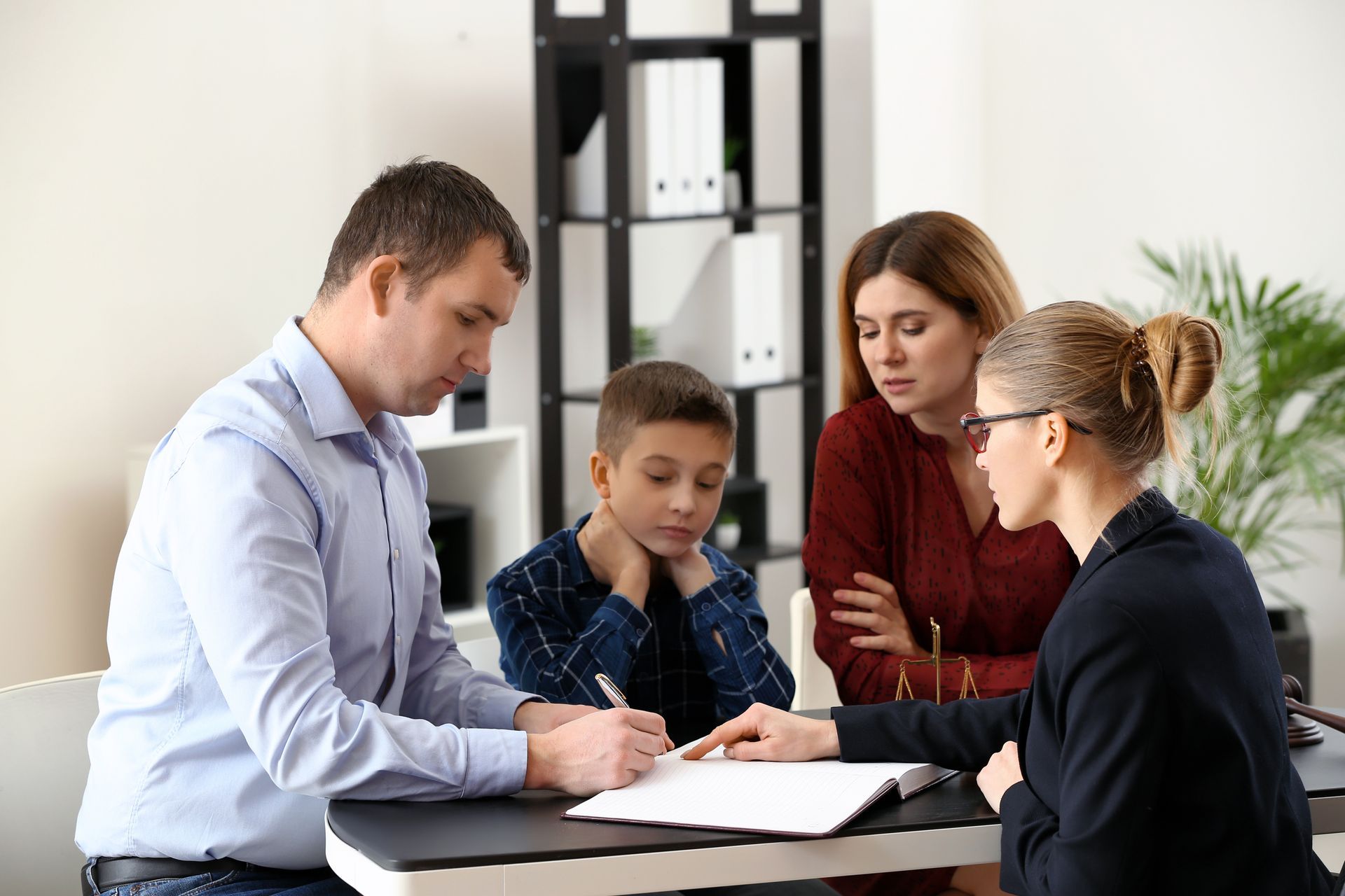 Four people review documents around a table in a bright office, discussing paperwork together. Four people review documents around a table in a bright office, discussing paperwork together.