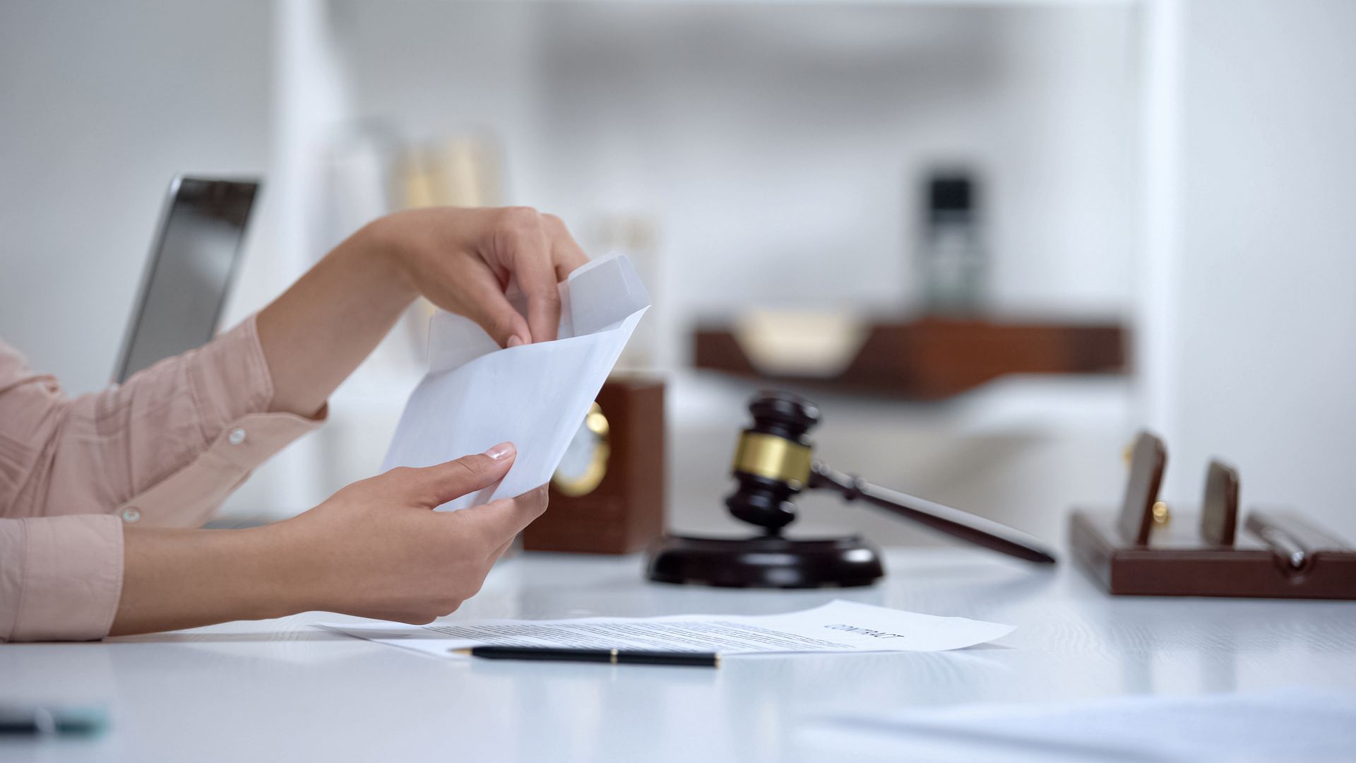 Hands sorting papers beside a gavel on a desk in an office setting Hands sorting papers beside a gavel on a desk in an office setting