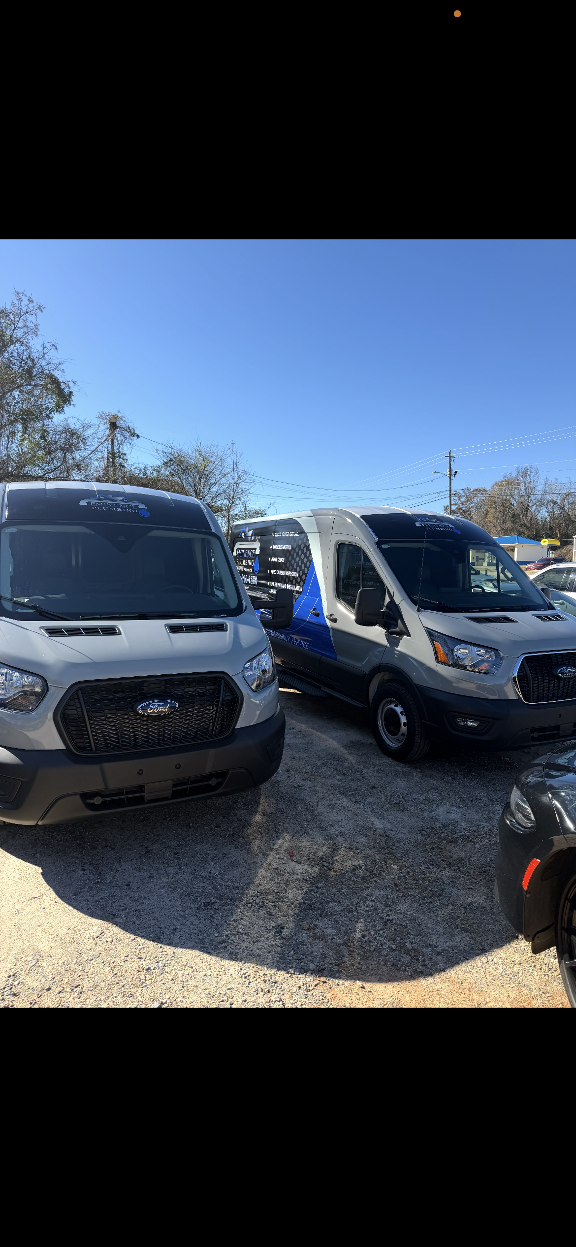 Two parked white vans under a blue sky. One has a blue accent.