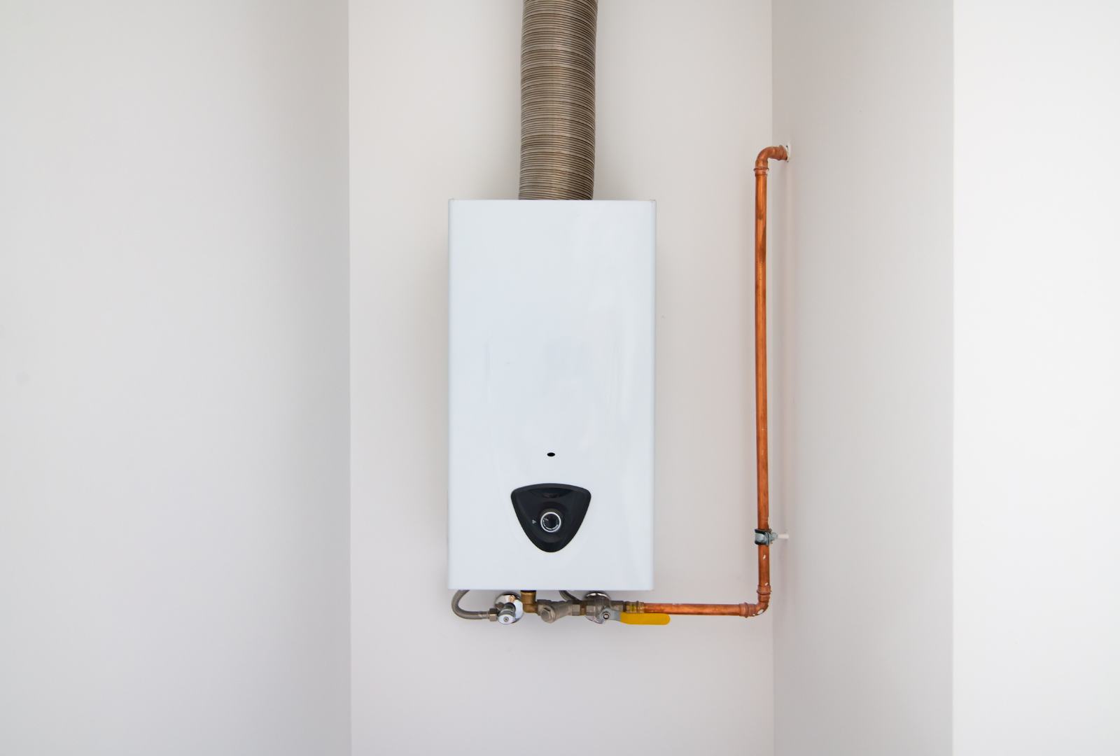 White wall-mounted gas water heater with copper pipes and ventilation duct.
