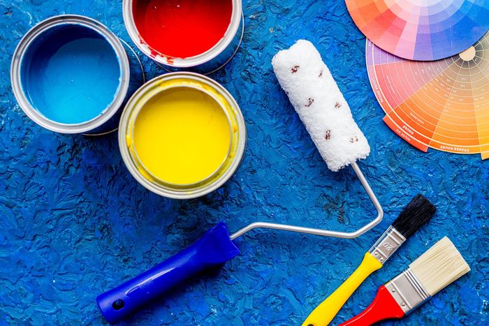 Paint cans , paint rollers , and brushes on a blue surface